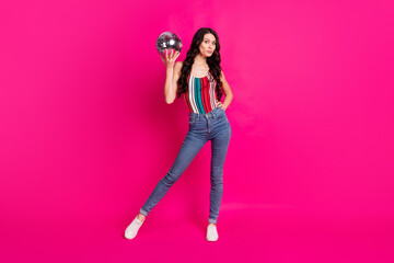 Full size photo of optimistic brunette lady hold disco ball wear top jeans sneakers isolated on vivid pink color background