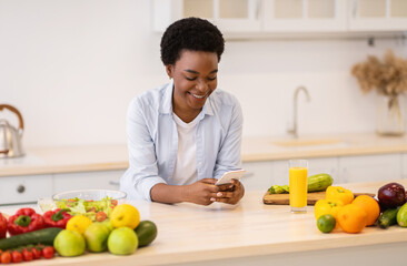African American Woman Using Smartphone Cooking Standing In Kitchen Indoor