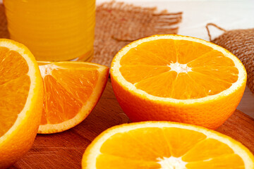 Glass of orange juice and cut oranges on table