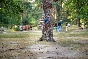 smiling boy rides a zip line. happy child on the zip line. The kid passes the rope obstacle course © pahis