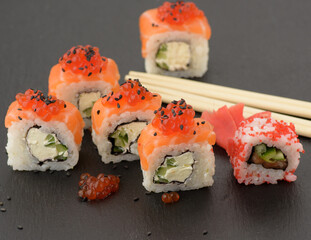 Philadelphia sushi with red caviar on a black slate board