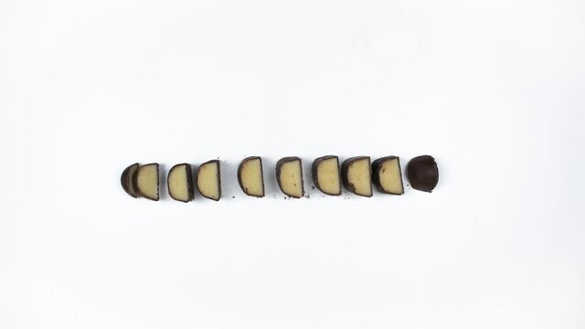 4k Chocolate covered marzipan bar wrapped in foil appears on a white background and is cut into pieces. Delicious sweet food concept. Stop motion animation.