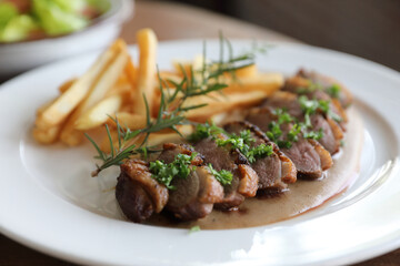 Duck magret confit with chips on wood table