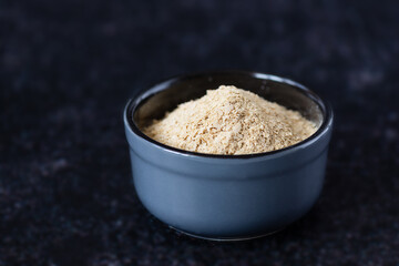 Dry yeast in a bowl on a dark background.