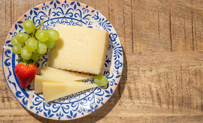 Cheese collection, piece of spanisch hard manchego cheese made in La Mancha region from sheep milk with green grapes and red strawberry