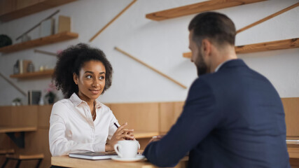 multiethnic business partners talking during meeting in cafe