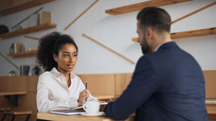 Fototapeta premium interracial business partners talking during meeting in cafe