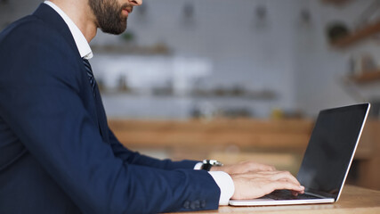 cropped view of bearded businessman typing on laptop