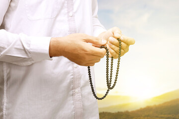 Muslim man praying with prayer beads on his hands