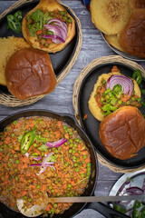 Indian pav bhaji served in cast iron dishes on wooden table