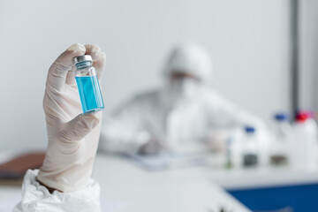 Obraz premium Jar with blue vaccine in hand of scientist in laboratory
