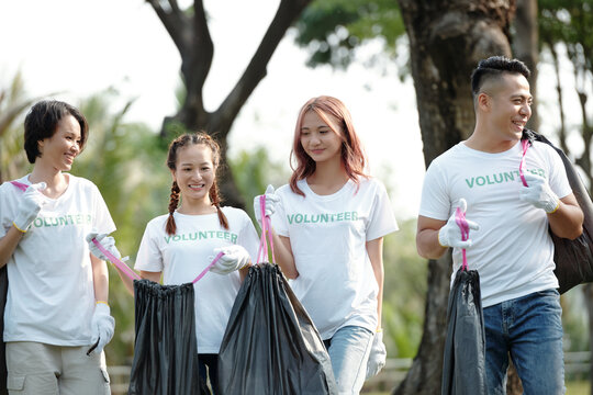 Cheerful Students In Volunteer T-shirts Packing Trash In Park On College Campus