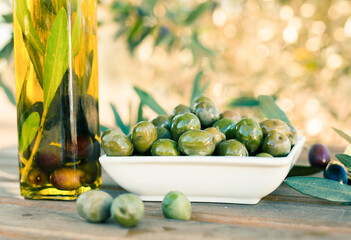 green olives and oil on table in olive grove