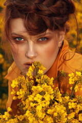  Young fashion model portrait with ginger hair and blue eyes in yellow rapeseed field