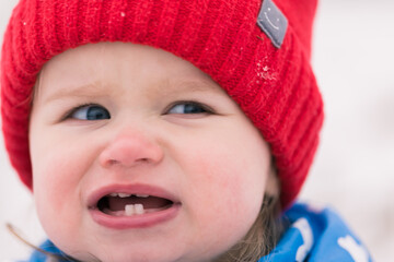 Cute toddler girl with blue eyes and red hat. Warmly dressed. Winter background.