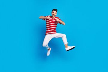 Fototapeta na wymiar Full body photo of happy brunette positive young man show thumbs-up jump air isolated on blue color background