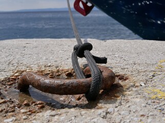 A black rope made of synthetic material holds the yacht at the pier against the background of the...