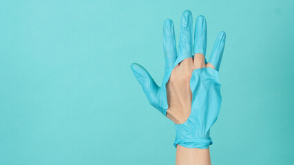 Hand Wearing torn medical gloves or torn rubber gloves on blue and green  or Tiffany Blue color background.monotone coclor.
