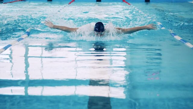 Front view of a man swimming butterfly in slow motion
