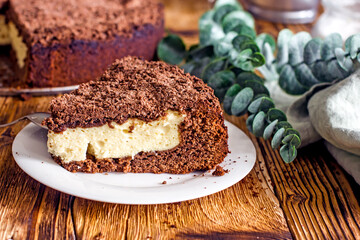 A piece of homemade chocolate pie with curd filling on a plate on a wooden table, close-up