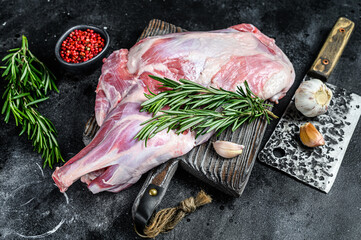 Raw lamb shoulder meat ready for baking with garlic, rosemary. Black background. Top view