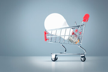 Light Bulb In The Shopping Cart On Blue Background. Energy Supplier To Save Money Concept.