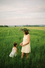 mom and daughter in the field. summer time. women have a wreath of wildflowers
