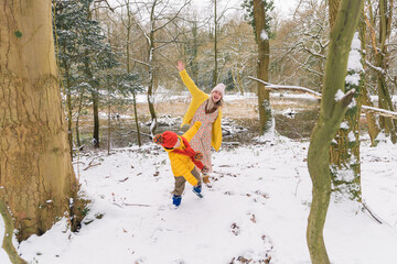 Loving mother and her son have fun in the forest. Background winter forest.