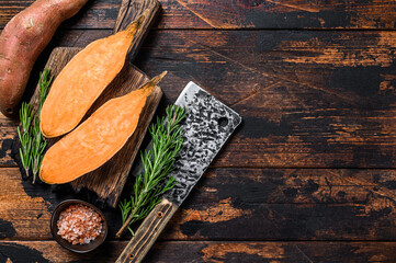 Raw cut Sweet potato on Wooden cutting board. Dark wooden background. Top view. Copy space