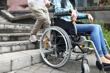 Man tries to drag wheelchair with woman onto stairs