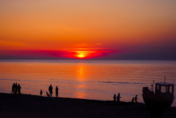 Fototapeta na wymiar People at sunset on the beach