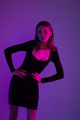 Girl portrait in neon light. Young slim woman model in black dress