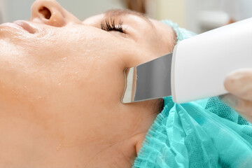 Naklejka premium A gloved beautician cleanses the skin on the face using a special gel and equipment. The concept of facial hygiene, cosmetic procedures, skin care, skin pore cleansing, hardware cosmetology.