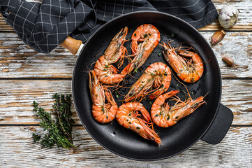 Fried giant tiger shrimps Prawns in a pan. White wooden background. Top view