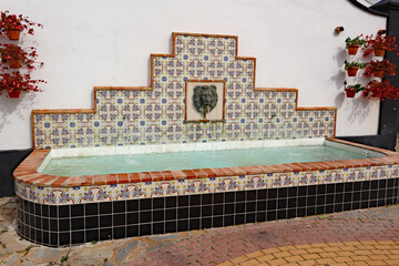 A water feature with a lion's head on a ceramic tile background in a public plaza in Estepona in Spain