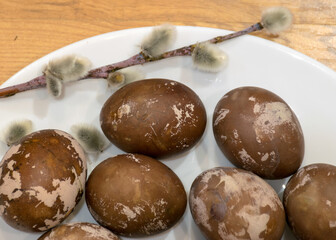Easter eggs on a plate, European Easter with traditional decoration eggs, easter eggs decorated with natural fresh leaves and boiled in onions peels and blueberry berries