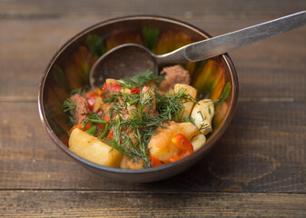 Potatoes with meat and vegetables in a plate on a wooden background. uzbek cuisine oriental soup, roast....