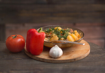 Potatoes with meat and vegetables in a plate on a wooden background. uzbek cuisine oriental soup, roast.