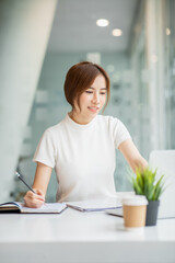 Asian Young Woman working on laptop. Freelancer at remote work. Female student learning on-line via computer. Blogger or journalist writing new article.