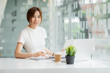 Asian Young Woman working on laptop. Freelancer at remote work. Female student learning on-line via computer. Blogger or journalist writing new article.