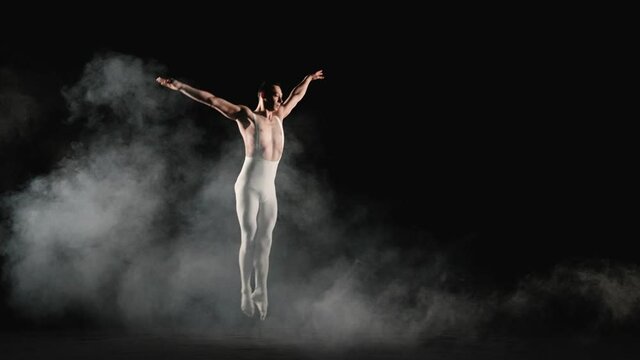 Ballet dancer performs acrobatic element on a black background. Slow motion