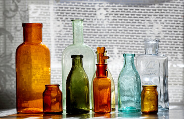 Antique glass bottles on a table next to a window