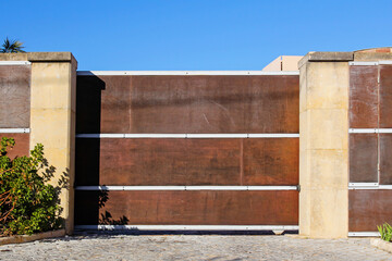 Fototapeta na wymiar elegant modern wooden fence with automatic gate against blue sky