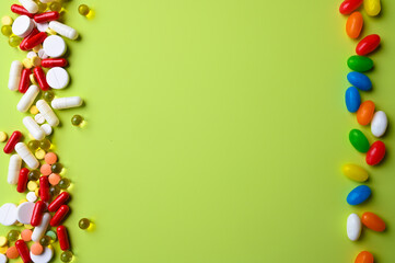 Top view of colorful bright pills and vitamins on pastel green background