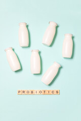 Small bottles with probiotics and prebiotics dairy drink on blue background. Production with...