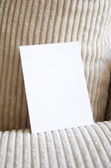 Greeting card, postcard, invitation mock up on cozy apparel background in interior. Flat lay.