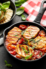 Grilled halloumi cheese and tomato bake served in cast iron skillet, close-up. Delicious vegetarian food.