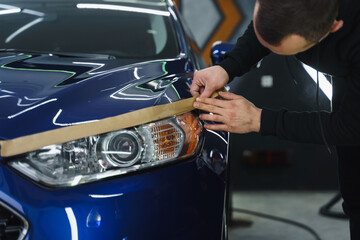 Man prepares car headlights for polishing..