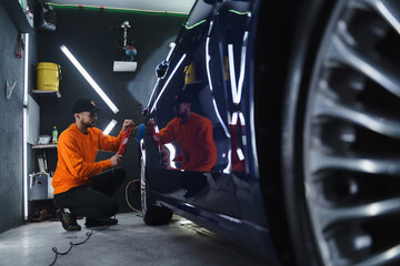 Man in a mask polishes car