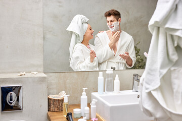 young caucasian couple doing daily morning procedures in bathroom